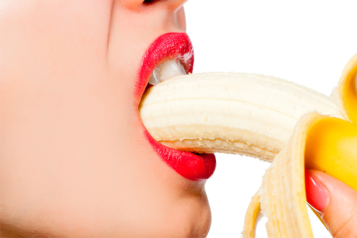 Femme sensuelle au rouge à lèvre avec une banane dans la bouche